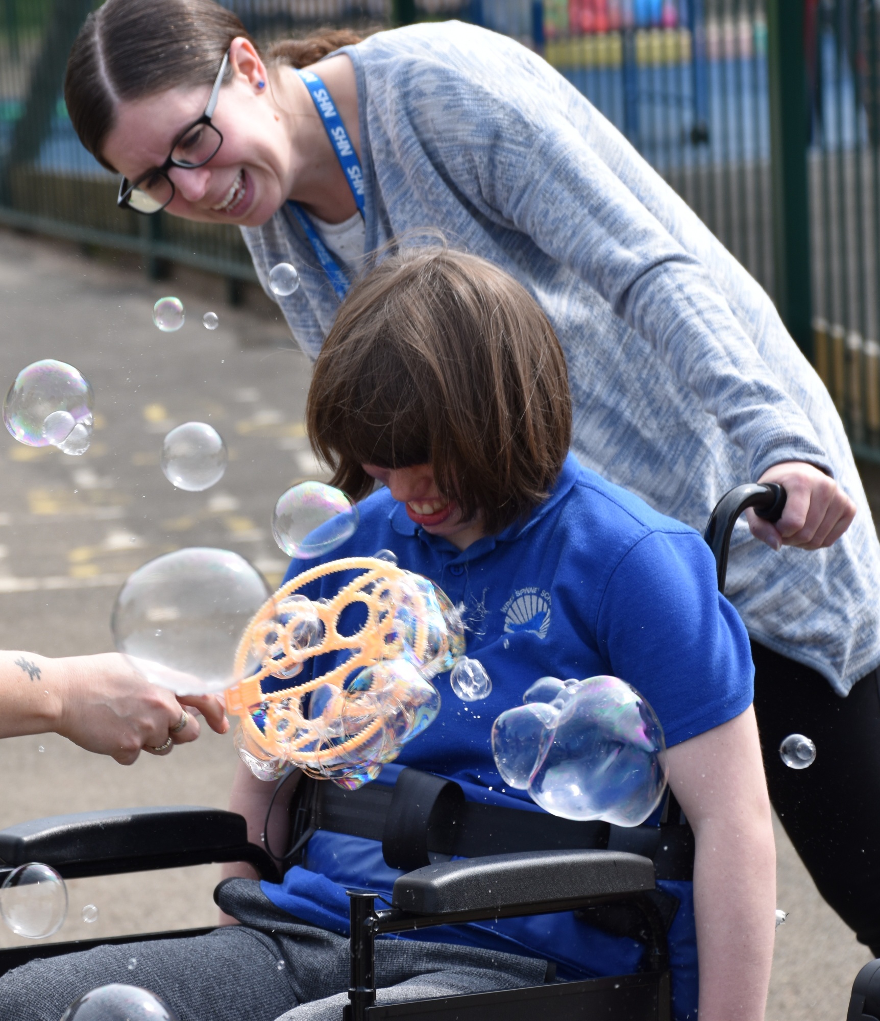 Teacher with student in wheelchair having fun with bubbles at Wren Spinney